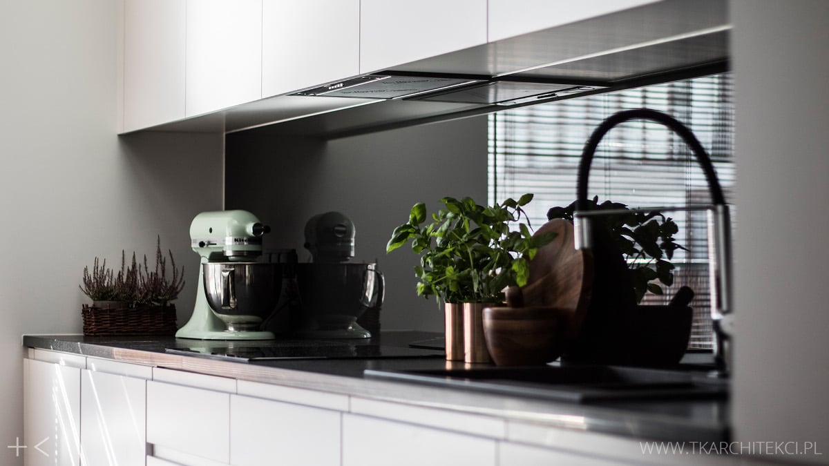 Białe meble kuchenne z czarną ścianą nad blatem | proj. TK Architekci